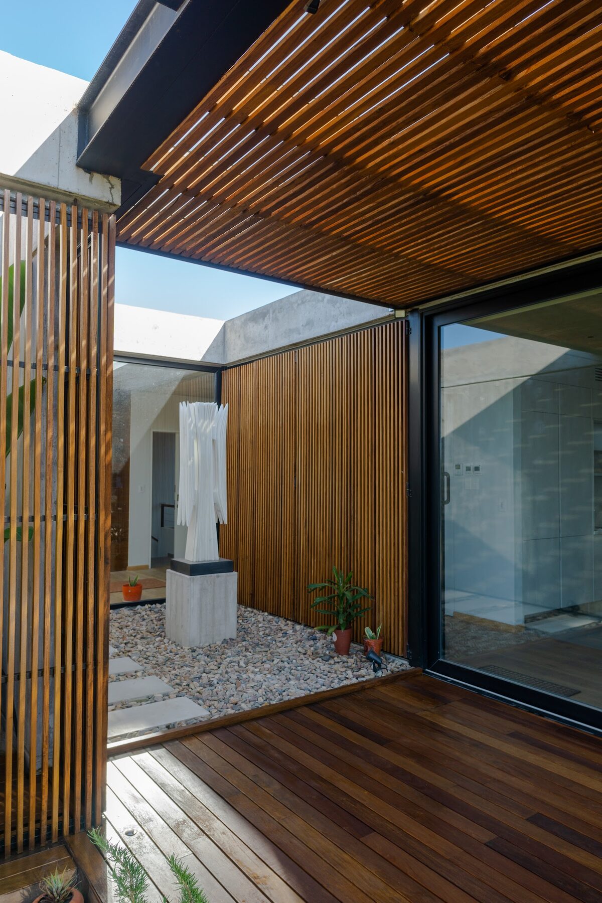 patio interior con deck de madera, pérgola y tamices