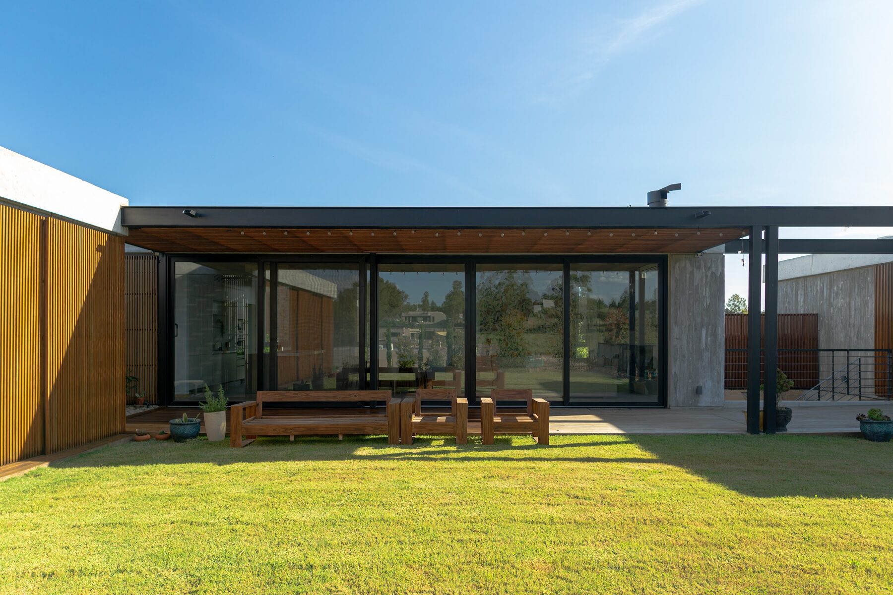 galería con pérgola de hierro y estar exterior al atardecer