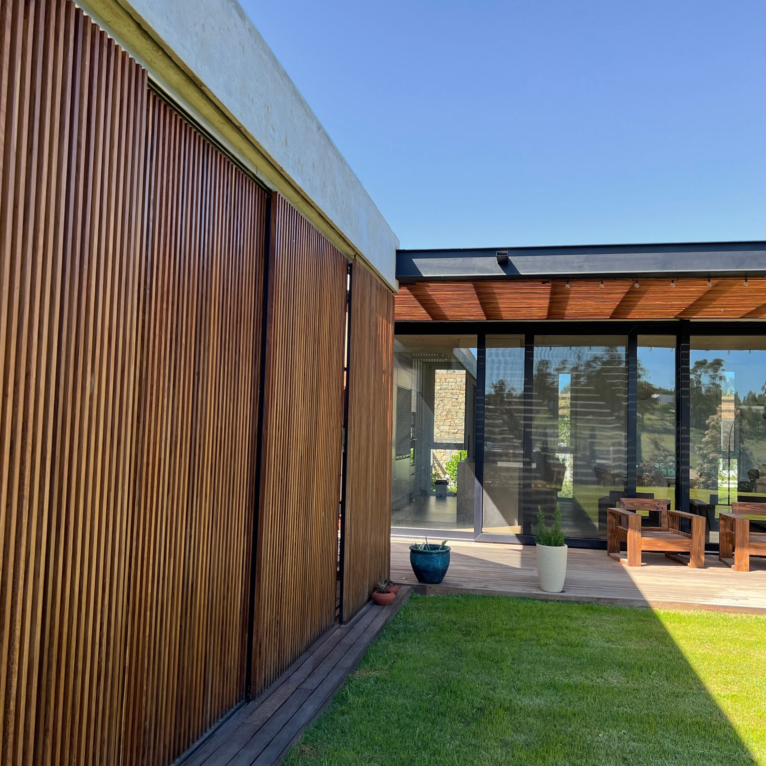 Casa patio con tamices de madera, hormigón visto y galería vidriada