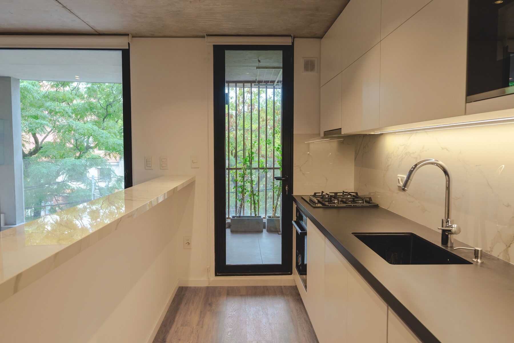 cocina con mesada oscura y ventanal al verde