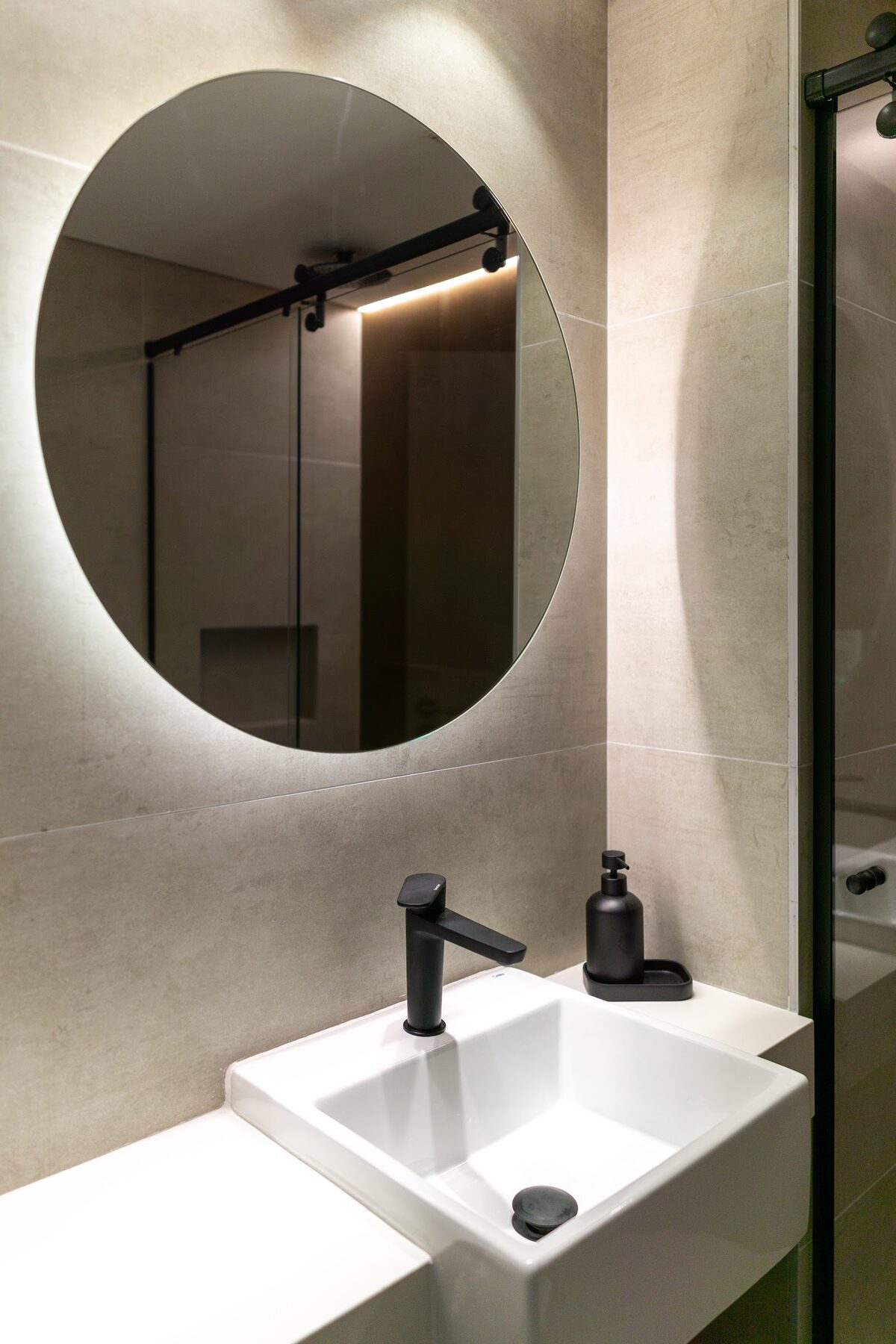 baño con espejo redondo y lavatorio blanco