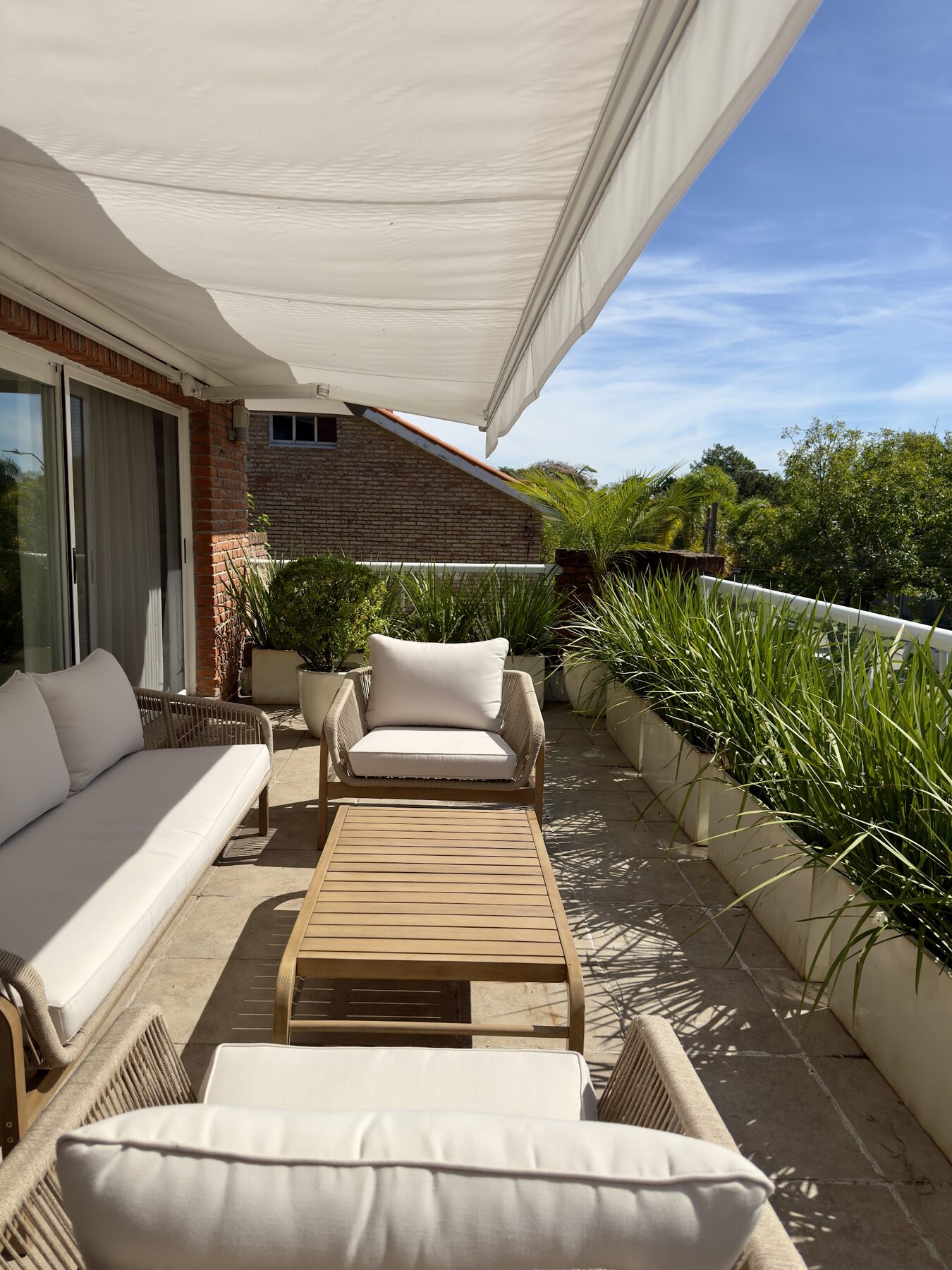 terraza con toldo, sillones y vegetación