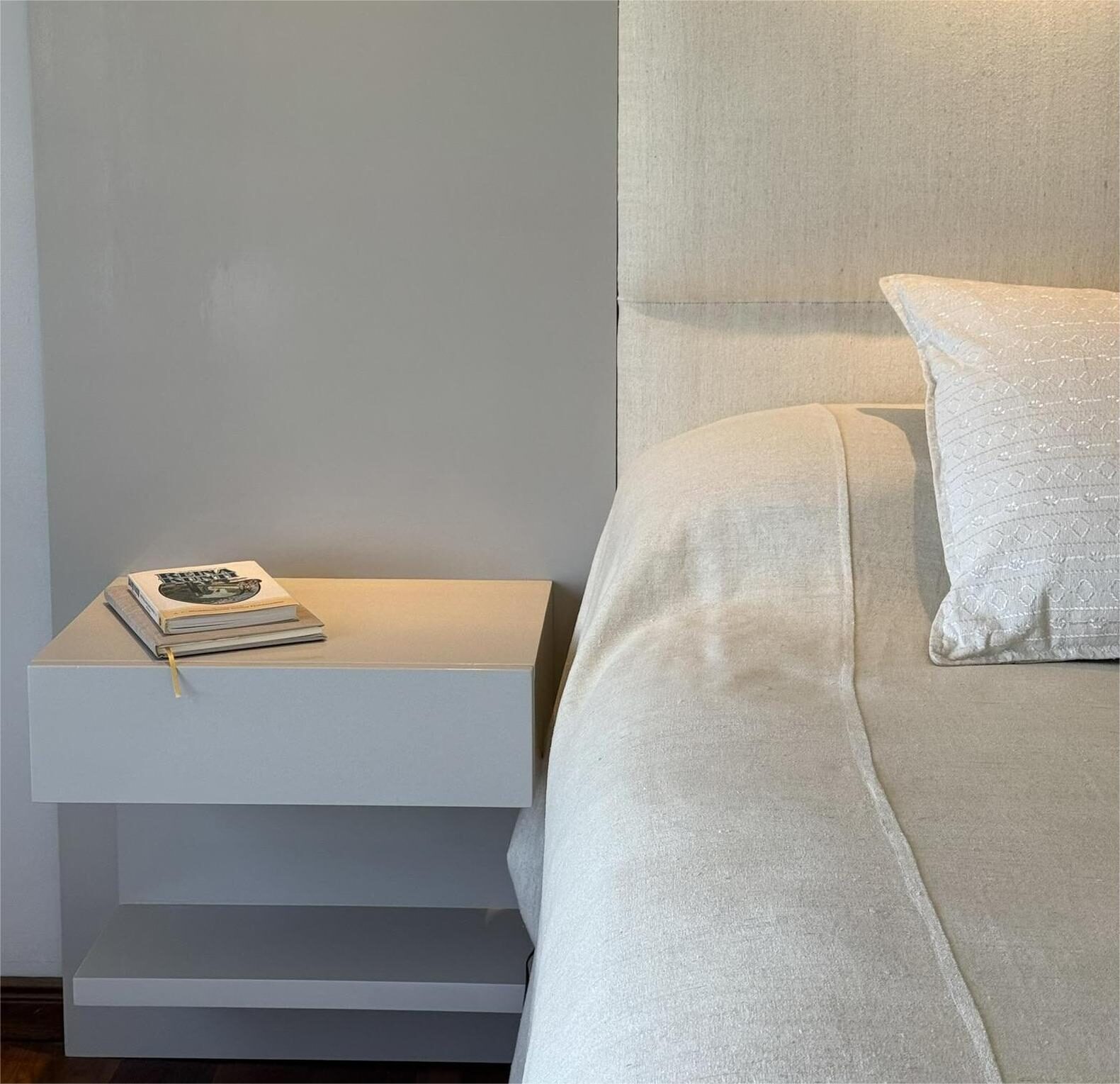 mesa de luz blanca junto a la cama con ropa de lino